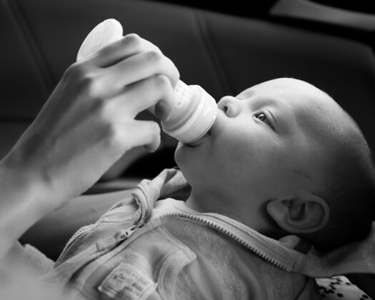 牛奶灰阶特写一个人喂养一个新生的孩子在灯光下与模糊的背景塑料喂养小