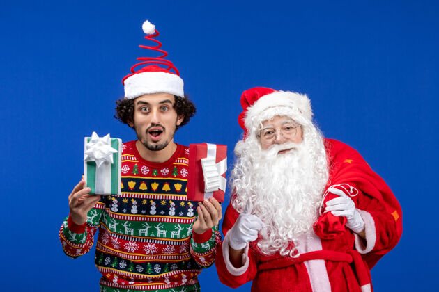 人们正面图：圣诞老人和手持礼物的年轻男性圣诞老人举行情感