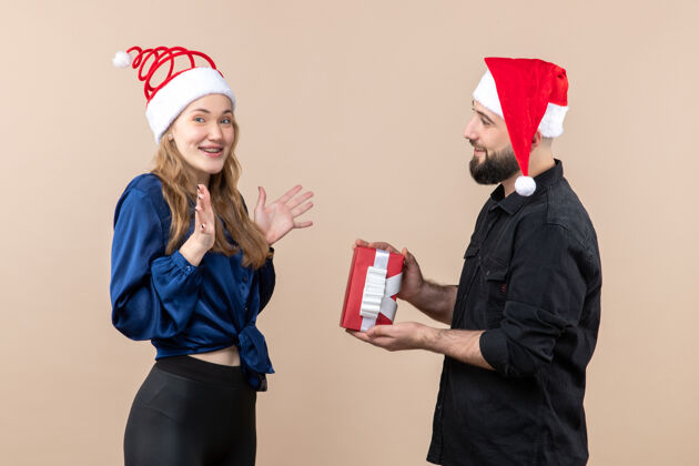 快乐年轻女子和送她礼物的男人在粉红色墙上的正视图模特节日圣诞快乐