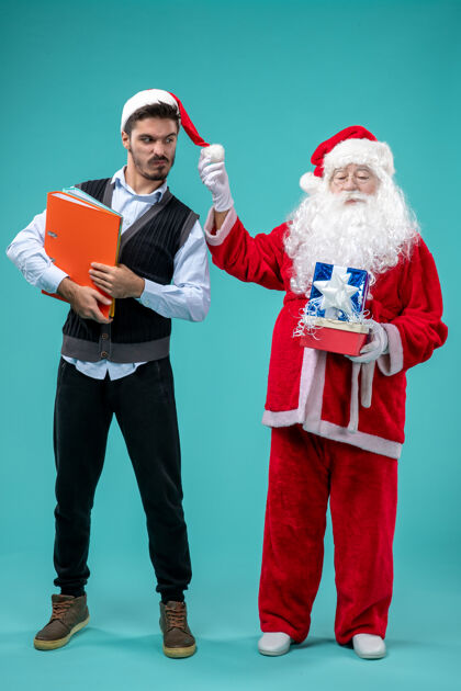 圣诞老人前视图圣诞老人与年轻的男性和礼物上的蓝色背景年轻圣诞老人圣诞
