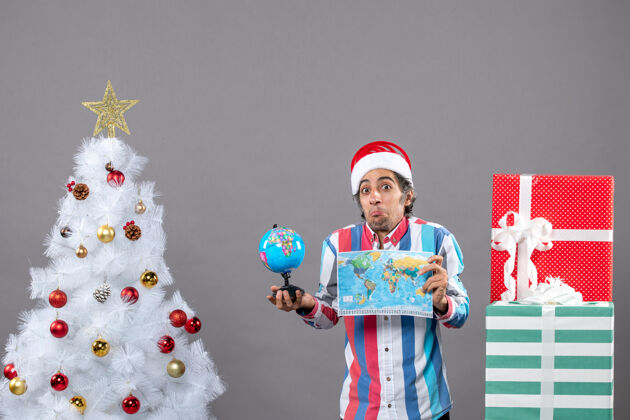 圣诞前视图撬人与螺旋弹簧圣诞帽举行世界地图和地球仪周围圣诞树和礼物假期礼物旅行