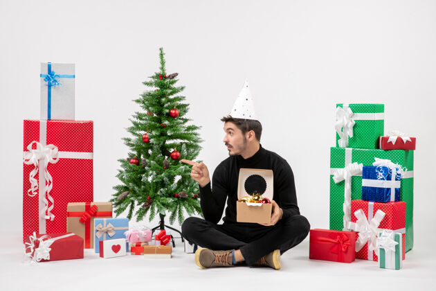 装饰年轻人围坐在白墙上的礼物面前坐节日圣诞树