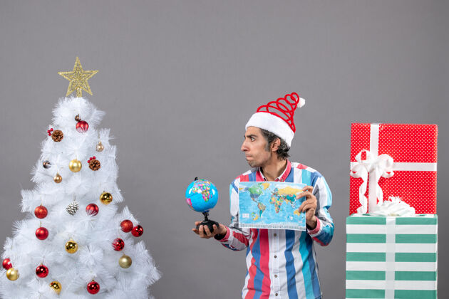帽子前视图奇迹中的人与螺旋弹簧圣诞帽举行世界地图和地球仪奇迹中的人旅行旅行者
