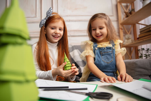 圣诞节圣诞树两个孩子 女孩一起创造快乐的孩子为游戏或新年庆祝手工玩具小白种人模型快乐的童年 庆祝准备工艺学前班女孩
