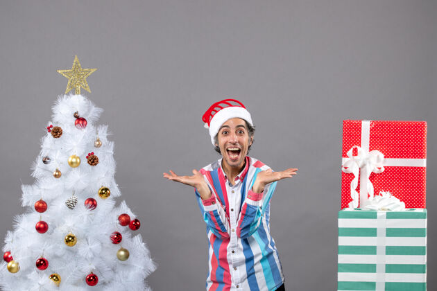 人正面图：快乐的男人张开双手站在白色圣诞树旁男火炬圣诞节