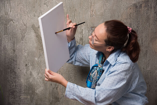大理石坐在画布上用画笔在大理石背景上画东西的女人画布女性刷子