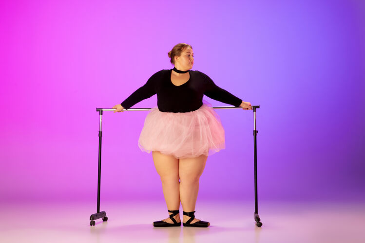 身体积极美丽的高加索人模特在霓虹灯下的渐变紫粉色工作室背景上练习芭蕾舞激励 包容 梦想和成就的理念值得成为芭蕾舞演员灵感执行芭蕾舞