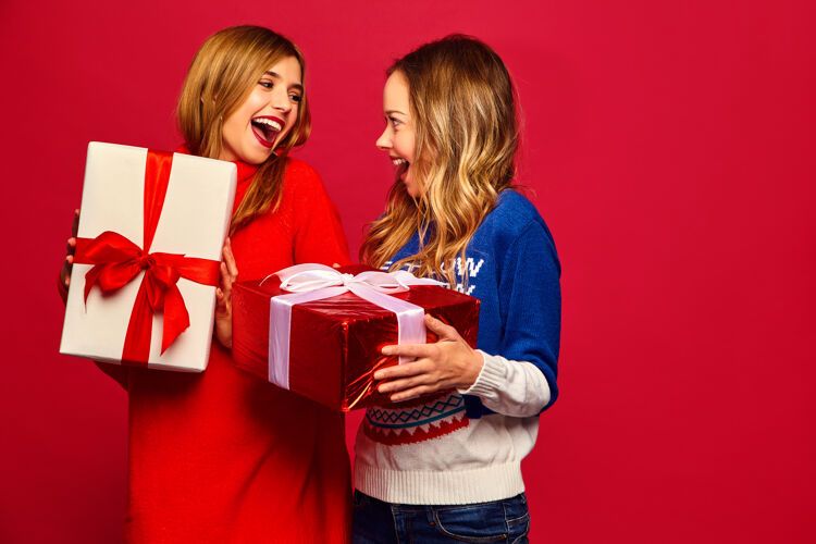 时尚两个微笑的漂亮女人穿着时髦的毛衣和大礼盒青少年性感青少年