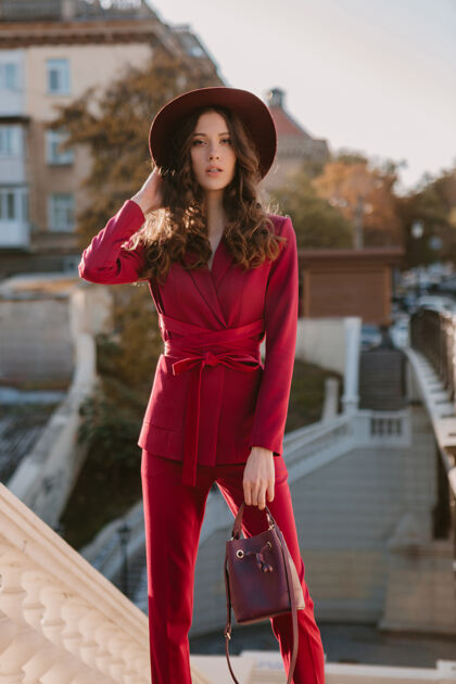 套装穿着紫色西装的漂亮时髦女人走在城市街头 春夏秋冬时节时尚潮流戴着帽子 手拿钱包女人秋天深色