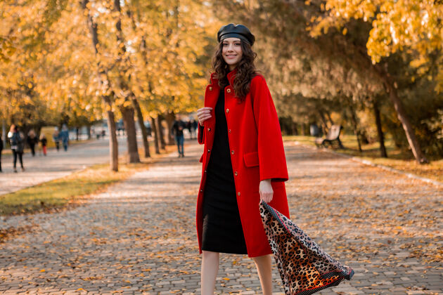夹克迷人时尚微笑的女人卷发漫步在公园穿着暖红色外套秋季时尚 街头风格 戴贝雷帽和豹纹围巾女性优雅穿着