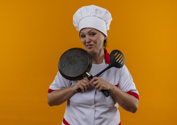 抹刀穿着厨师制服的中年女厨师手拿煎锅和抹刀厨师平底锅煎炸