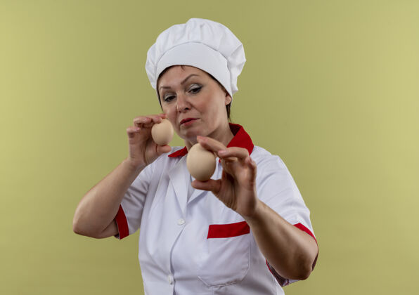 思考穿着厨师制服的中年女厨师看着手里的鸡蛋女性鸡蛋厨师
