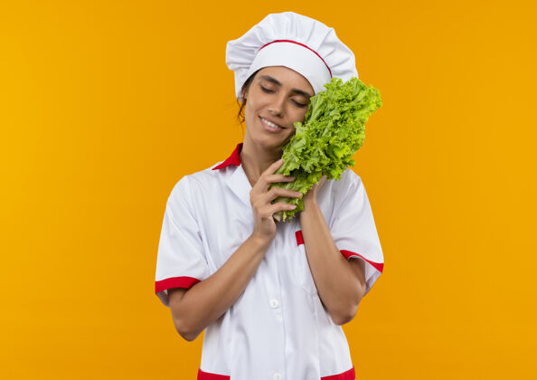 高兴合上眼睛高兴的年轻女厨师穿着厨师制服 把沙拉放在脸颊上 留着复印空间穿制服面颊