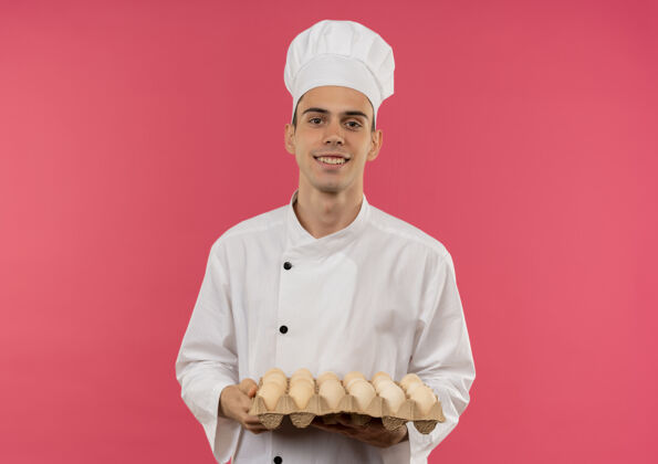 持有微笑的年轻男厨师穿着厨师制服拿着一批鸡蛋厨师男穿