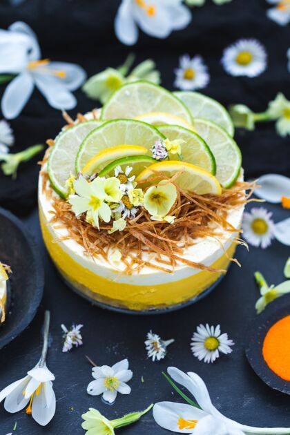 派生的纯素蛋糕 柠檬和酸橙在黑色的表面覆盖着小雏菊花水果花香蕉
