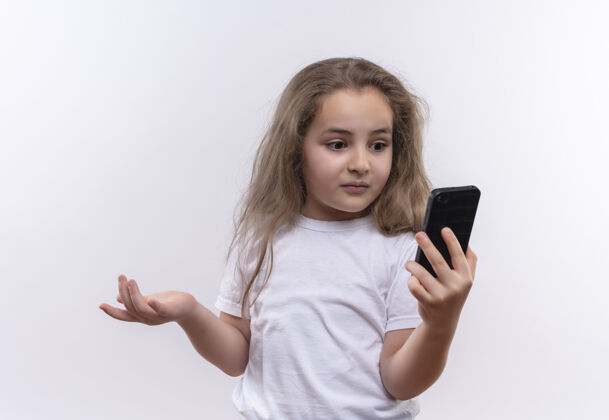 电话惊讶的小女生穿着白色t恤看着手机上孤立的白色背景学校女孩惊讶