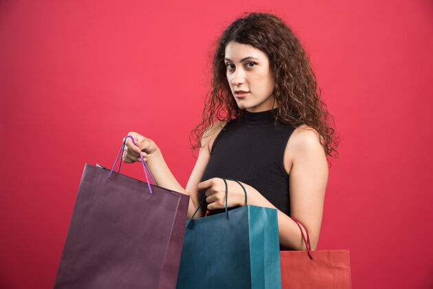 购物在红色背景上展示新买衣服的女士高质量照片新女性服装