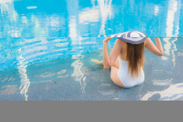 游泳肖像美丽的亚洲年轻女子放松微笑周围的室外游泳池在酒店度假村热带放松泳装