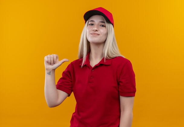 年轻穿着红色t恤和帽子的年轻女孩在孤立的橙色背景上指着自己红色橙色高兴