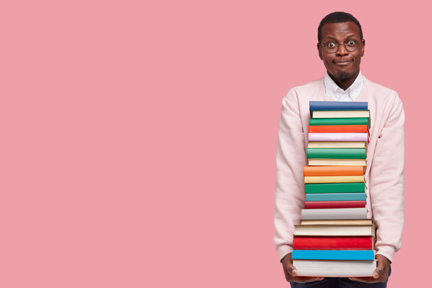 学生迷茫的黑人拿着一堆书 穿着休闲毛衣 戴着眼镜外观当代大学