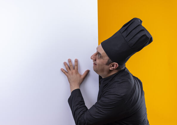 中年站在剖面图中年男性厨师在厨师制服举行黄色背景白色墙壁与复制空间制服厨师男