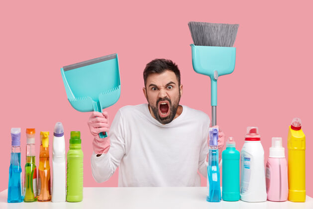 脏愤怒恼怒的没刮胡子的男人忙着打扫屋子 拿着勺子和扫帚 坐在桌子旁喷着清洁喷雾家务家务房子