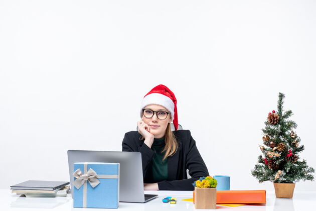 行政人员在办公室里 年轻漂亮的女士坐在一张桌子旁 桌上放着圣诞树和一份礼物圣诞树人圣诞节