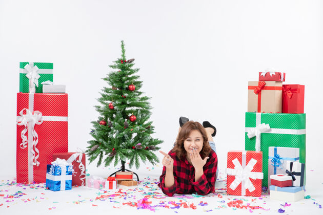 冬青正面图年轻女性躺在圣诞礼物和圣诞树上 白色背景礼物圣诞新年彩雪周围礼物年轻