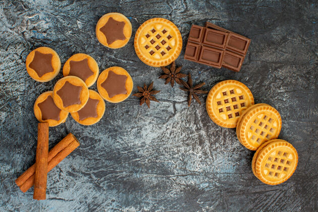 灰色月牙形饼干的俯视图 灰色背景上有肉桂和巧克力巧克力形状棍棒
