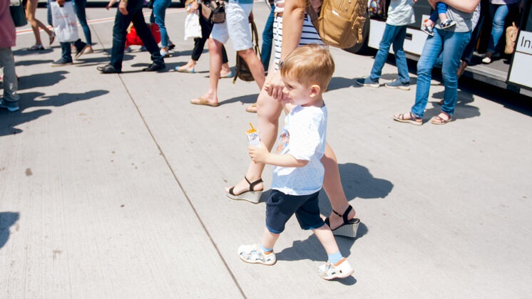 小可爱的小男孩牵着妈妈的手走出机场的巴士班车观看街道婴儿