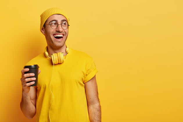 人类乐观的戴眼镜的男人笑着和朋友们一起喝咖啡 拿着一次性杯子 看向别处T恤杯子笑