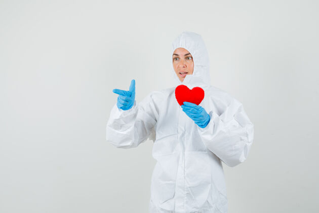 套装女医生一边指着一边拿着红心穿防护服健康年轻实验室