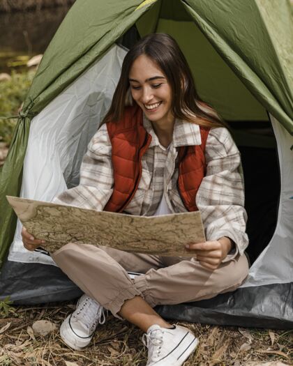 旅行快乐的野营女孩在森林里查看地图和微笑木材度假旅行