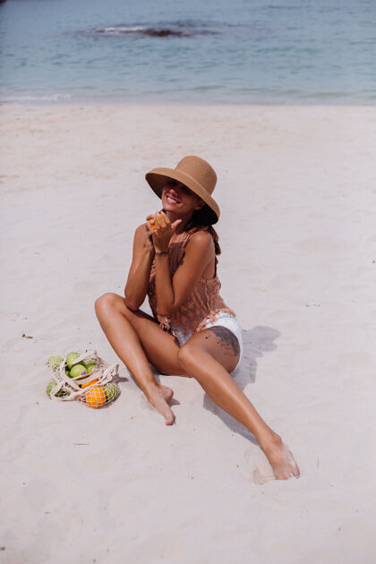 女性年轻漂亮的白种人 皮肤黝黑 穿着针织衣服 戴着帽子在沙滩上款式肖像服装