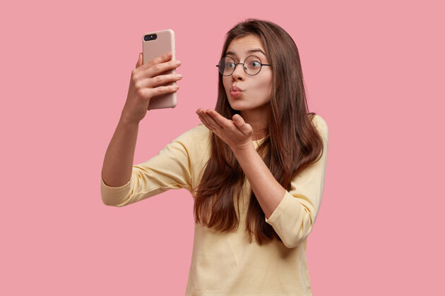 毛衣漂亮的白种女人对着手机镜头做空中接吻 和远方的男友视频通话 调情道别休闲视频通话手机