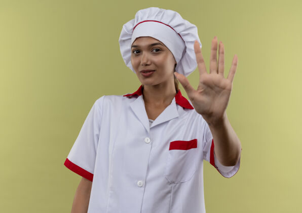 穿着身着厨师制服的年轻女厨师在与世隔绝的绿墙上做着停车的手势制服展示高兴