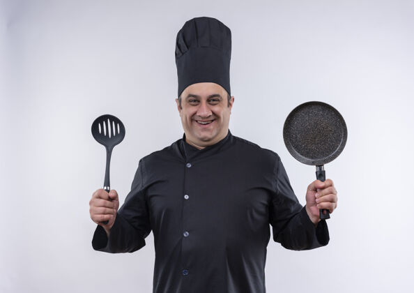 平底锅微笑的中年男厨师 身着厨师制服 手里拿着抹刀和煎锅制服抹刀厨师