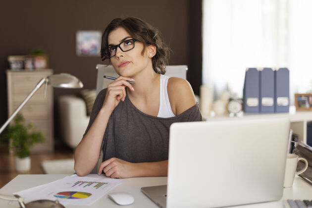 位置在家工作的体贴女人眼镜笔笔记本电脑