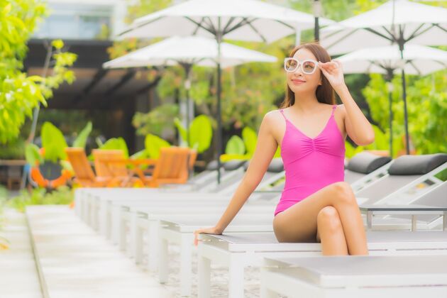 游泳肖像美丽的亚洲年轻女子放松微笑周围的室外游泳池在酒店度假村泳装享受性感