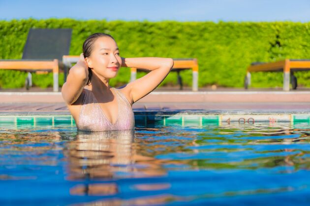 海滩美丽的亚洲年轻女子在度假酒店的室外游泳池周围放松的肖像热带放松游泳