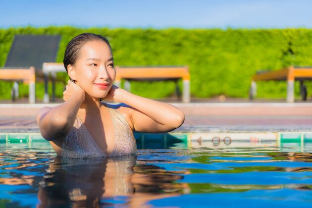 漂亮美丽的亚洲年轻女子在度假酒店的室外游泳池周围放松的肖像放松游泳阳光