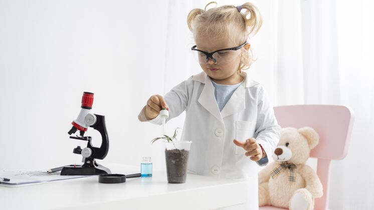 研究可爱的幼儿学习科学与植物和显微镜前视图实验外套植物