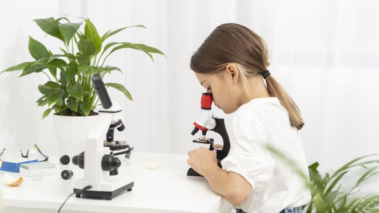 孩子年轻女孩看显微镜的侧视图显微镜水平科学