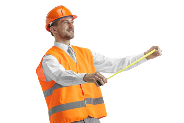 头盔穿着建筑背心和橙色头盔的建筑工人站在白色的工作室里工业工业男人