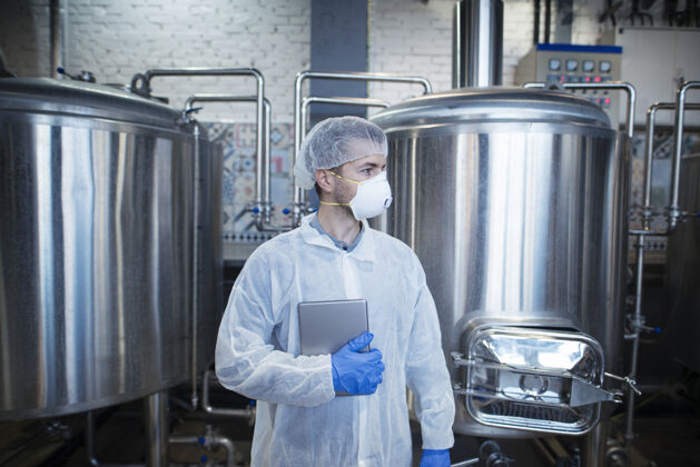 发网专业经验丰富的工艺师 穿着白色防护服 手持药片 在食品生产厂一旁观望操作员制服技术员
