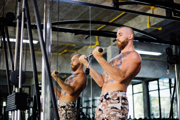 男性纹身的健康男人在健身房锻炼肌肉力量休闲