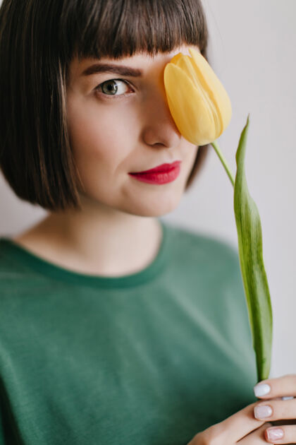 植物可爱的欧洲女人棕色头发的特写照片与花摆姿势室内肖像令人高兴的黄色郁金香时尚女孩幸福享受模特