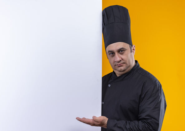 制服身穿厨师制服的中年男厨师手拿白墙 黄墙上有临摹空间男厨师抱着