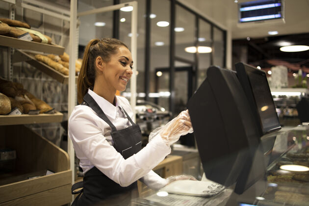 商店女面包师在电脑上工作 在超市卖面包糕点打字深色头发