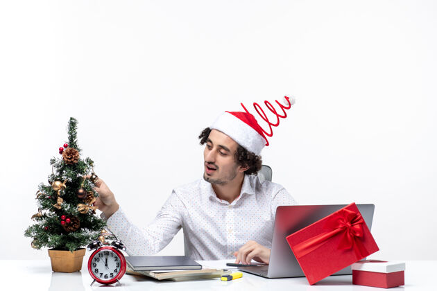 年轻商人满意的年轻商人与有趣的圣诞老人帽子装饰圣诞树和庆祝圣诞节在白色背景的办公室圣诞老人笔记本电脑商人